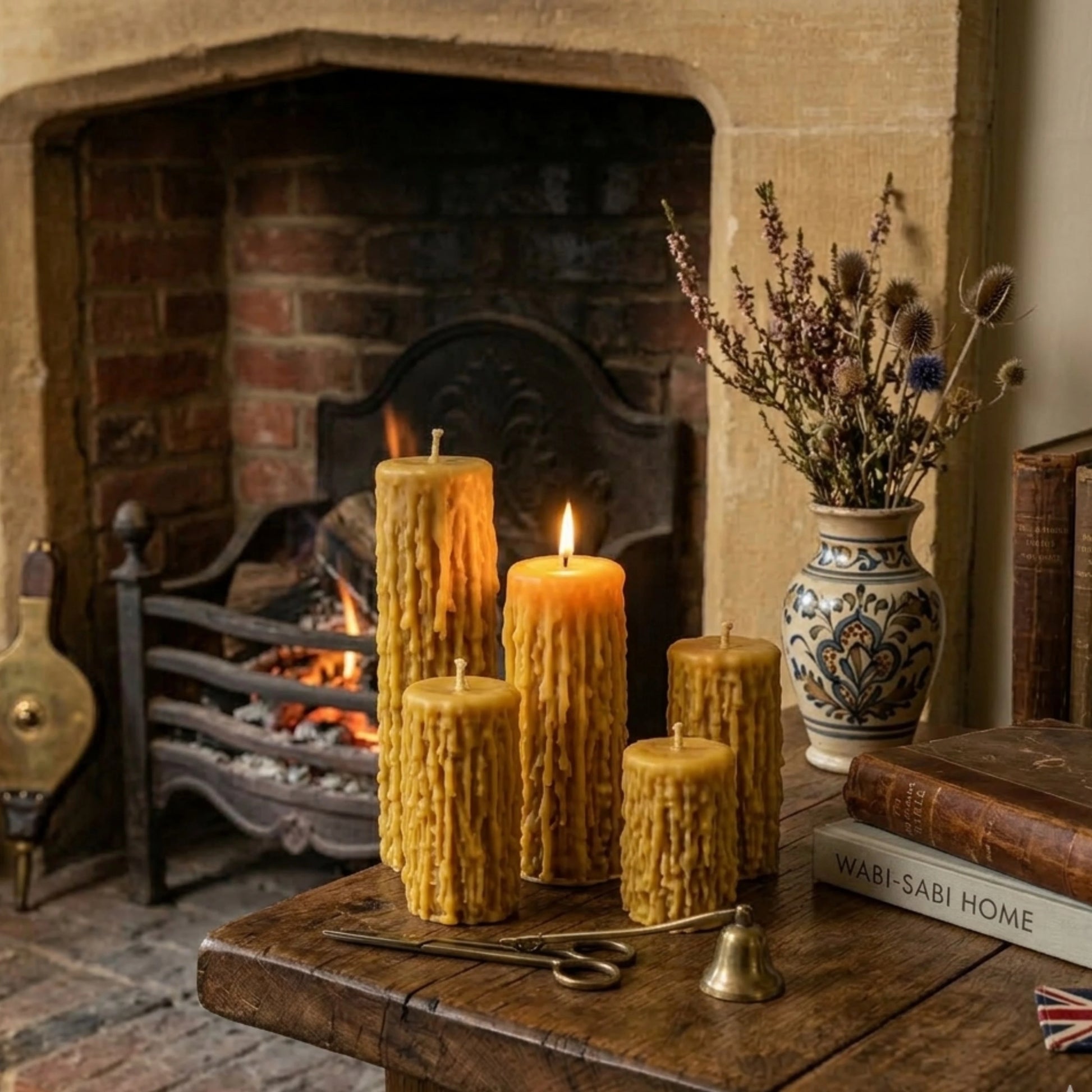 Four textured beeswax pillars arranged on a rustic oak table next to a traditional British stone fireplace, creating a cozy, Victorian-inspired atmosphere perfect for home decor.