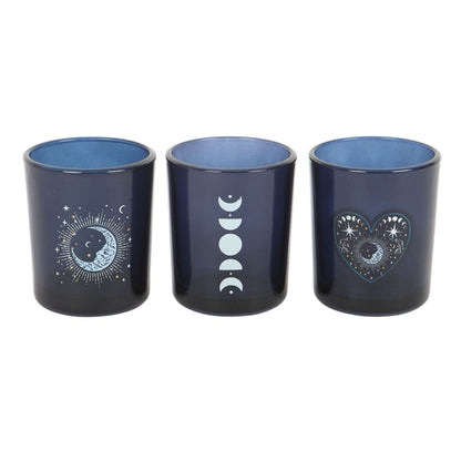 A set of 3 cobalt blue glass votive holders with intricate silver astrology prints, perfect for spiritual home decor.
