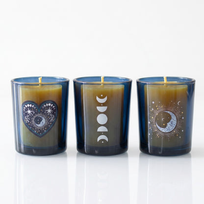 Trio of dark blue glass celestial tealight holders featuring silver moon phases and a mystical heart emblem on a white background.