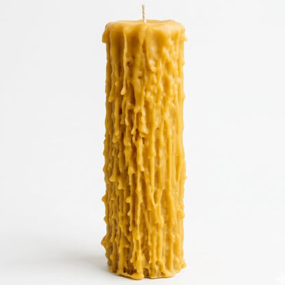 A single, extra-tall beeswax pillar candle with a rustic gothic drip effect, standing centered on a white surface to showcase its elegant proportions and natural honey-colored wax.